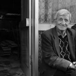 A serene black and white portrait of an elderly man sitting outside a café in Istanbul.